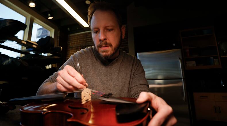 Andrew Henke, co-owner of Ronald Sachs Violins in Avondale Estates, works on a violin in his repair shop on Wednesday, Jan. 28, 2026. New tariff policies have increased prices on imported string instruments. Henke now orders fewer instruments and instead is focused on selling back stock. (Miguel Martinez/AJC)