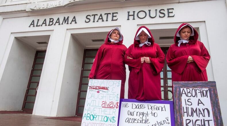 Bianca Cameron-Schwiesow, from left, Kari Crowe and Margeaux Hartline, dressed as handmaids, take part in a protest against HB314, the abortion ban bill, at the Alabama State House in Montgomery, Ala., on Wednesday April 17, 2019.