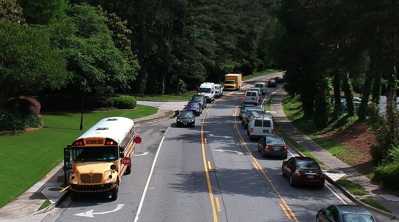 Fulton County Schools bus stops on Powers Ferry Road in Sandy Springs on Wednesday, May 23, 2018. A phrase added to a 15-page bill late in the Georgia legislative session has caused panic among officials responsible for getting children to and from school safely. HYOSUB SHIN / HSHIN@AJC.COM