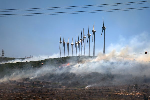 A fire rages near windmills in Cesme, near Izmir, Turkey, Thursday, July 3, 2025. (Cengiz Malgir/Dia Photo via AP)