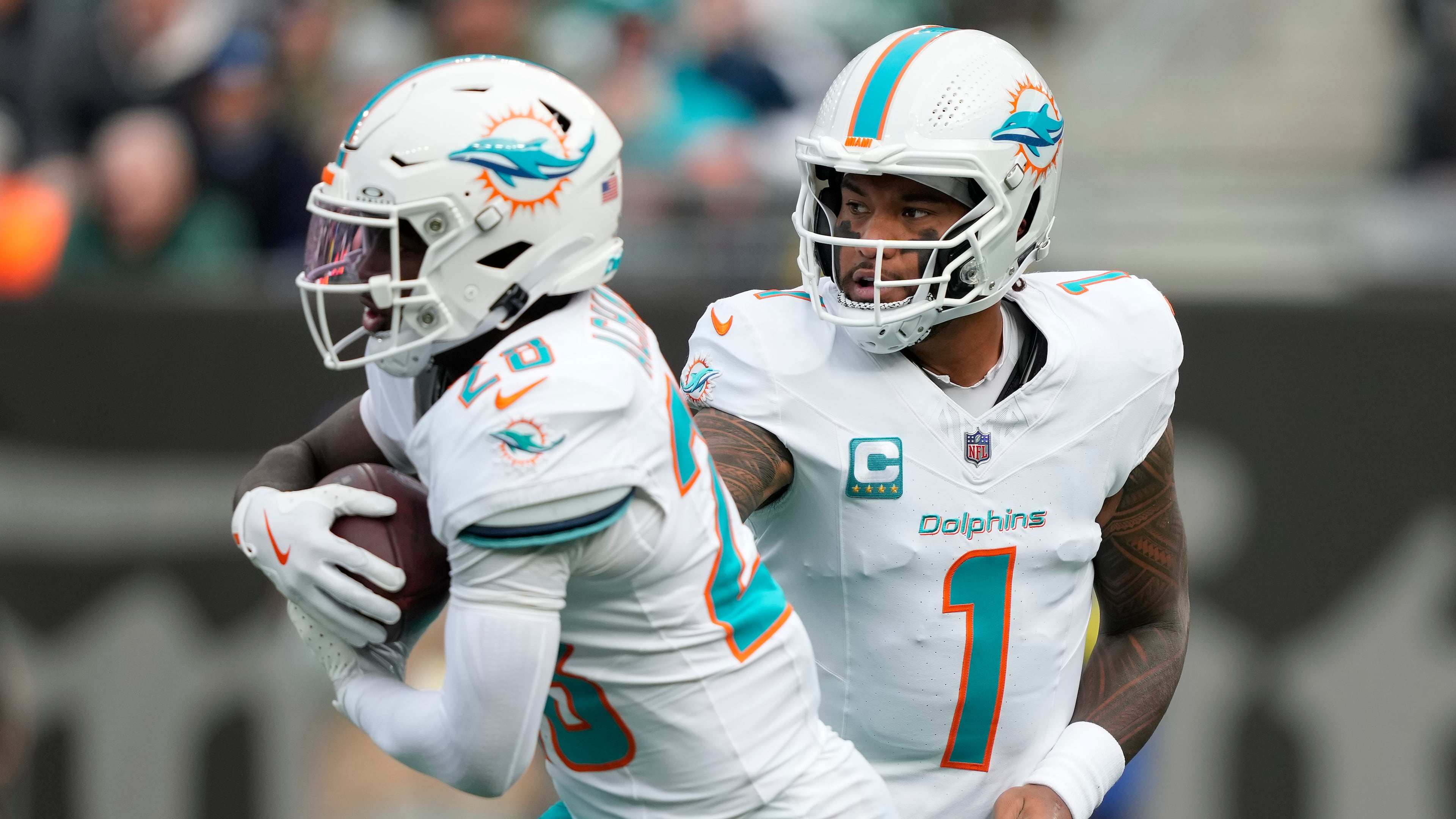 Miami Dolphins quarterback Tua Tagovailoa (1) hands off the ball to running back De'Von Achane (28) during the first quarter of an NFL football game, Sunday, Dec. 7, 2025, in East Rutherford, N.J. (AP Photo/Yuki Iwamura)