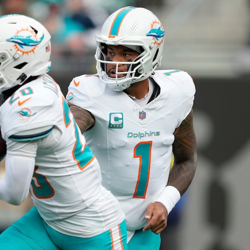 Miami Dolphins quarterback Tua Tagovailoa (1) hands off the ball to running back De'Von Achane (28) during the first quarter of an NFL football game, Sunday, Dec. 7, 2025, in East Rutherford, N.J. (AP Photo/Yuki Iwamura)