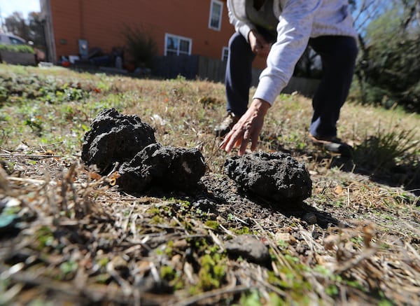 Rosario Hernandez rounds up chunks of slag, a byproduct of smelting, on the vacant lot next to her home near Mercedes-Benz Stadium on Nov. 25, 2019, in Atlanta. CURTIS COMPTON / CCOMPTON@AJC.COM