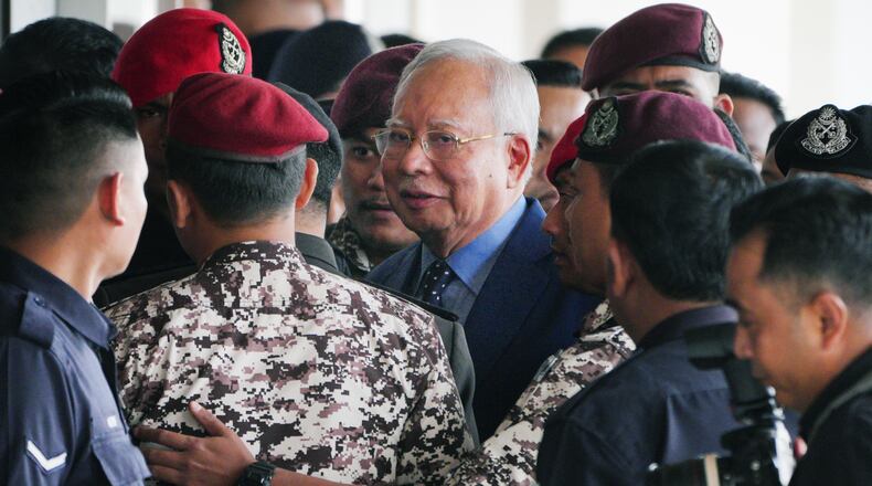 FILE - Malaysian former Prime Minister Najib Razak, center, is escorted by prison officers on his arrival at the Kuala Lumpur High Court complex in Kuala Lumpur, Malaysia, Oct. 30, 2024. (AP Photo/Vincent Thian, File)