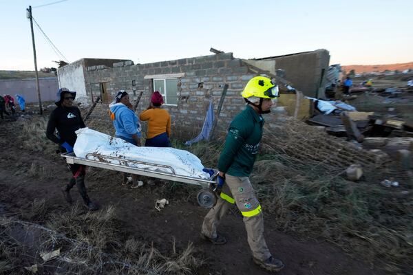 Rescue workers transport a person in a body bag after floods swept through the area in Mthatha, South Africa, Thursday, June 12, 2025. (AP Photo/Themba Hadebe)
