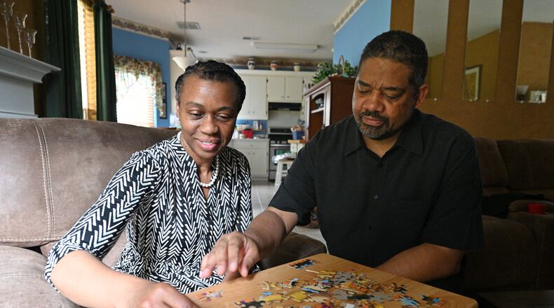 Robert Reid helps his wife Kim Reid, who was diagnosed with early-onset Alzheimer's, as she puts a puzzle together at their home in Hampton on Thursday, June 10, 2021. Hampton resident Robert Reid's wife, Kim, then 50, was diagnosed with early-onset Alzheimer's on June 15, 2017. (Hyosub Shin / Hyosub.Shin@ajc.com)