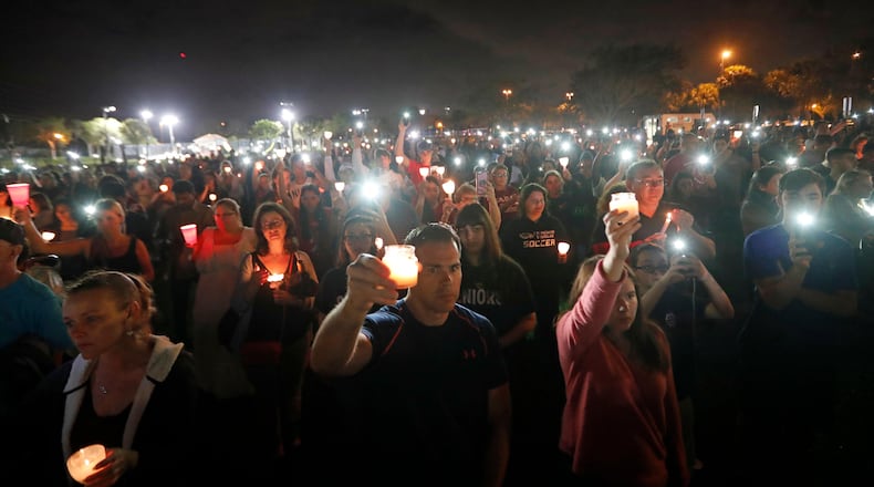 People participate in a candlelight vigil in memory of the 17 students and faculty who were killed in the Wednesday mass shooting at Marjory Stoneman Douglas High School in Parkland, Fla., Monday, Feb. 19, 2018. Nikolas Cruz, a former student, was charged with 17 counts of premeditated murder on Thursday. (AP Photo/Gerald Herbert)