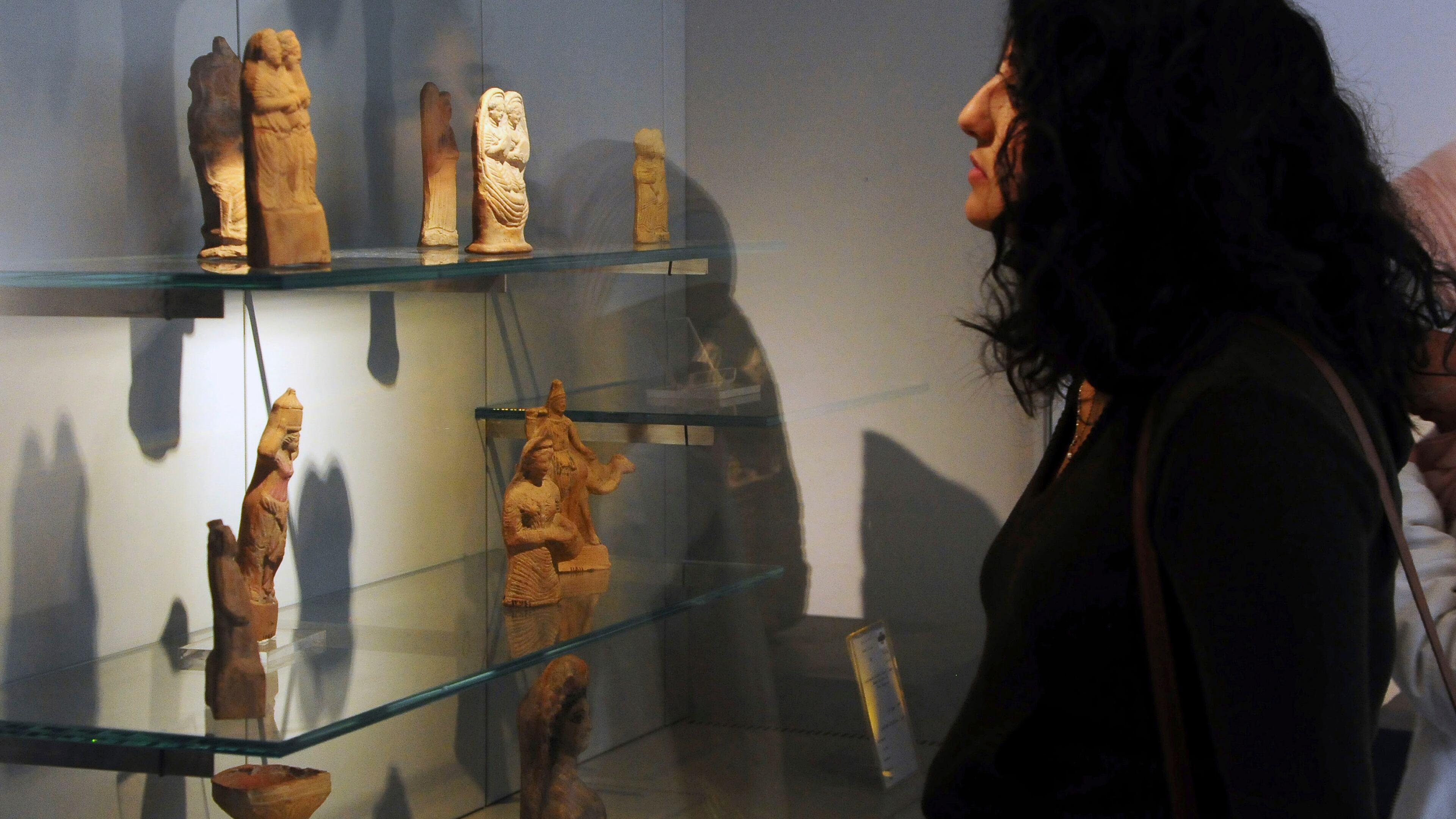 FILE - In this photo released by the Syrian official news agency SANA, a visitor looks at ancient artifacts during the reopening ceremony for Syria's National Museum, in Damascus, Syria, Oct. 28, 2018. (SANA via AP, File)