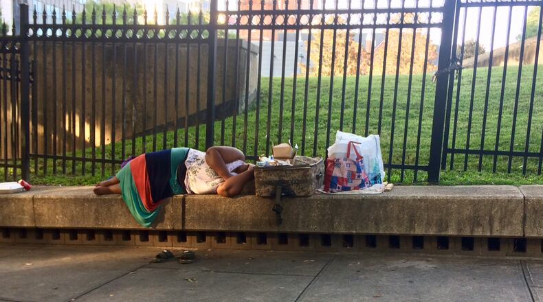 A woman sleeps on the ledge across from City Hall. Photo by Bill Torpy