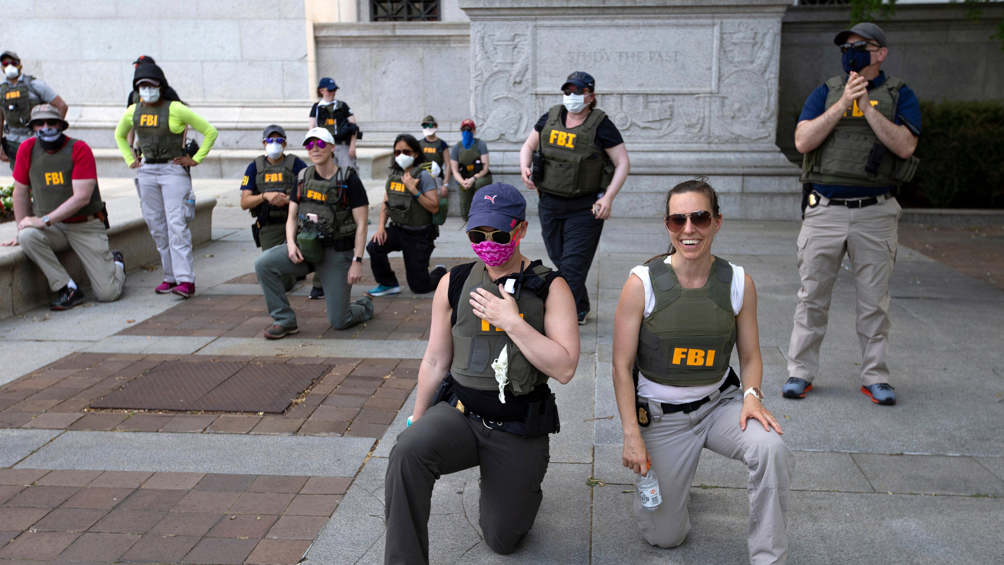 FILE - Federal Bureau of Investigation (FBI) officers take a knee with demonstrators, as they march on Pennsylvania Ave, June 4, 2020, in Washington, during a protest over the death of George Floyd, an unarmed black man, who died after a police officer kneeled on his neck for several minutes. (AP Photo/Jose Luis Magana, File)