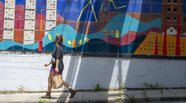 A woman wearing a mask walks along Ponce de Leon Avenue in Atlanta’s Old Fourth Ward community.(ALYSSA POINTER / ALYSSA.POINTER@AJC.COM)