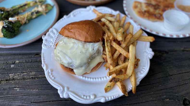 This takeout order from Woodward and Park includes grilled broccoli, smoked chicken (in background), pierogis and the house burger with fries. Wendell Brock for The Atlanta Journal-Constitution
