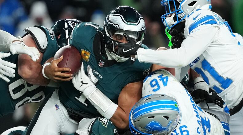 Philadelphia Eagles quarterback Jalen Hurts (1) is stopped with the ball during the second half of an NFL football game by Detroit Lions linebacker Jack Campbell (46) and Lions cornerback Amik Robertson (21) Sunday, Nov. 16, 2025, in Philadelphia. (AP Photo/Matt Slocum)