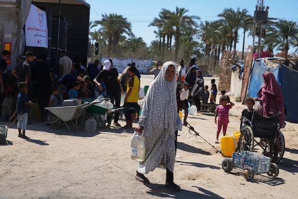 A Palestinian woman carries a container of water at a camp for the displaced in Deir al-Balah, Gaza Strip, Monday, July 7, 2025. (AP Photo/Abdel Kareem Hana)