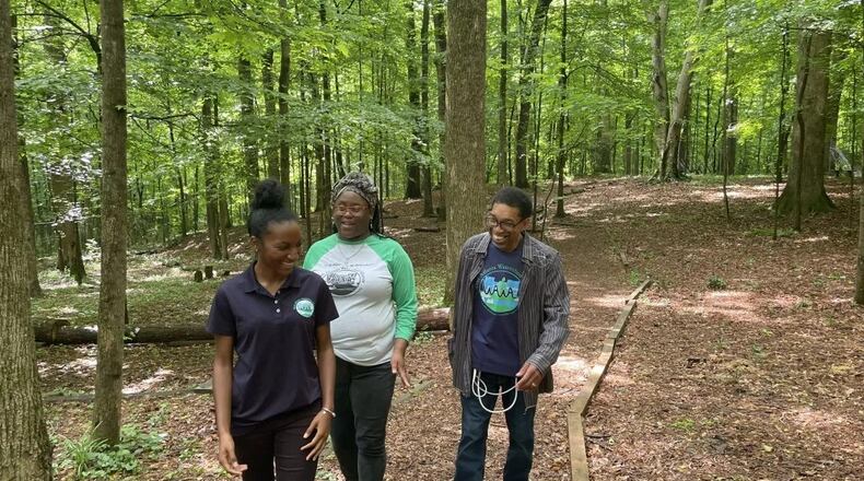 Destinee Whitaker (from left), Quanda Spencer, and Darryl Haddock with the West Atlanta Watershed Alliance walk through the woods at the Outdoor Activity Center, which WAWA operates for the city. (Photo Courtesy of Madeline Thigpen/Capital B)