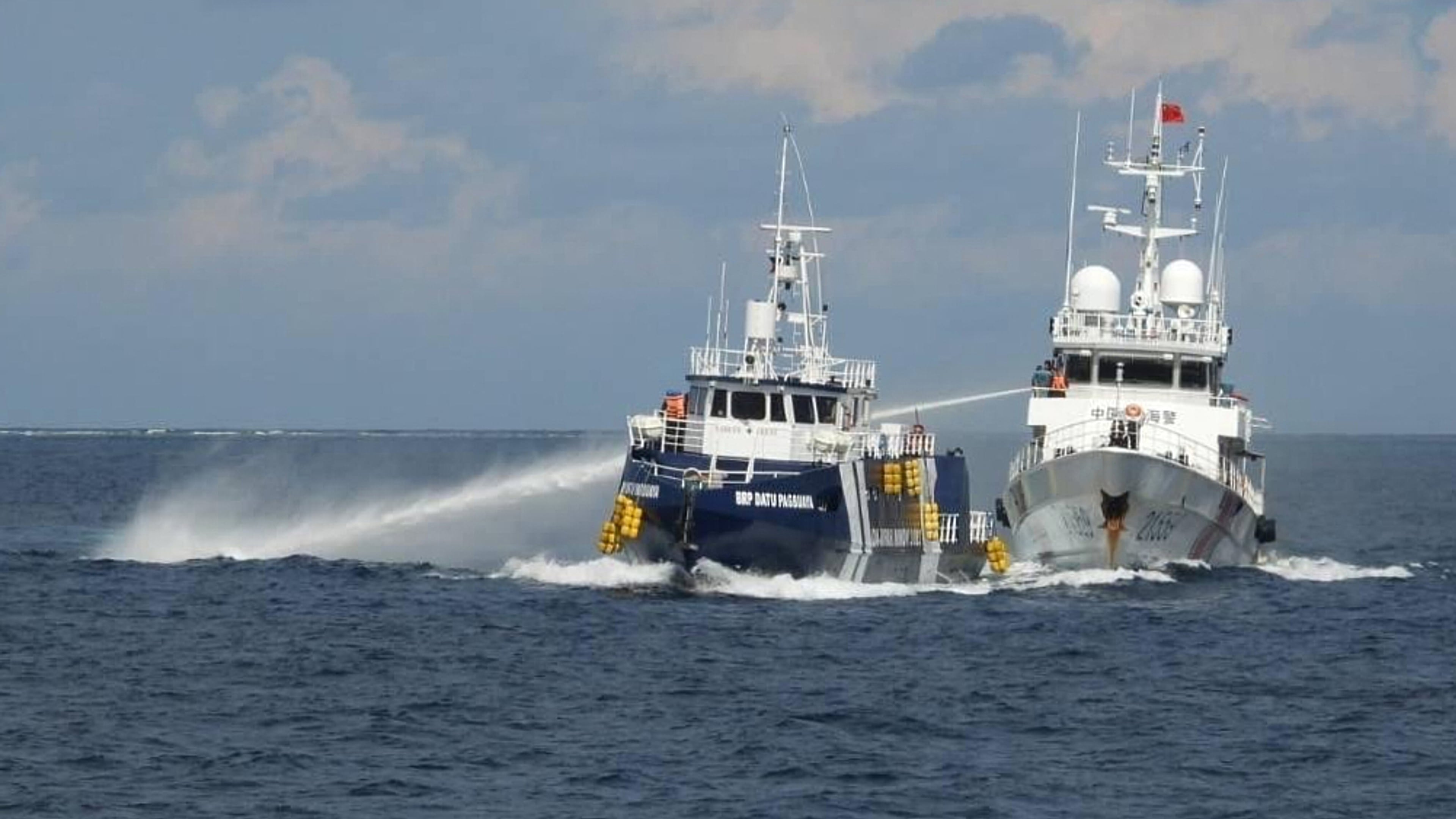 In this photo provided by the Philippine Coast Guard, a Chinese Coast Guard vessel, right, fires it's water cannon at the Philippine's BRP Datu Pagbuaya near Philippine occupied Thitu island locally called Pag-asa island at the South China Sea on Sunday Oct. 12, 2025. (Philippine Coast Guard via AP)