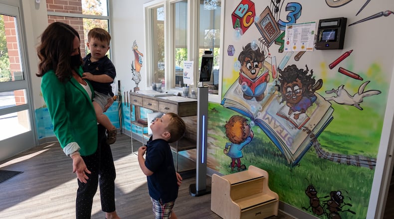 201014-Sandy Springs-Kim Sanders holds her son Eli, 2, and talks with her other son Rex, 3, while picking them up from The Goddard School of Sandy Springs on Wednesday afternoon, October 14, 2020. Sanders, who also has a 6-year-old daughter,l said there is no way she could work as an accounting consultant without a school for the kids to go to. Normally she would go to her sons’ classrooms to pick them up, but the COVID-19 safety measures include a staff member bringing children to the lobby and only one family is allowed in at a time. Ben Gray for the Atlanta Journal-Constitution