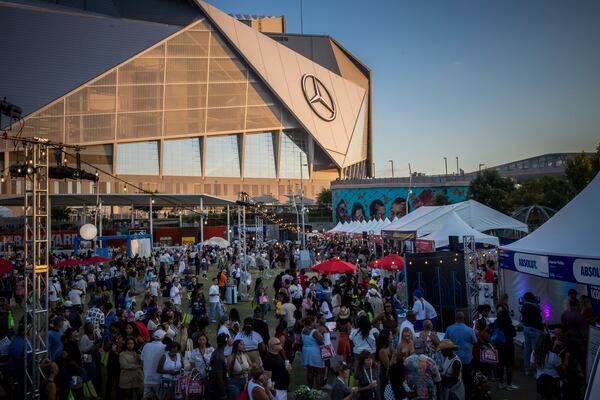 A crowded food festival takes place in front of Mercedes-Benz Stadium at golden hour