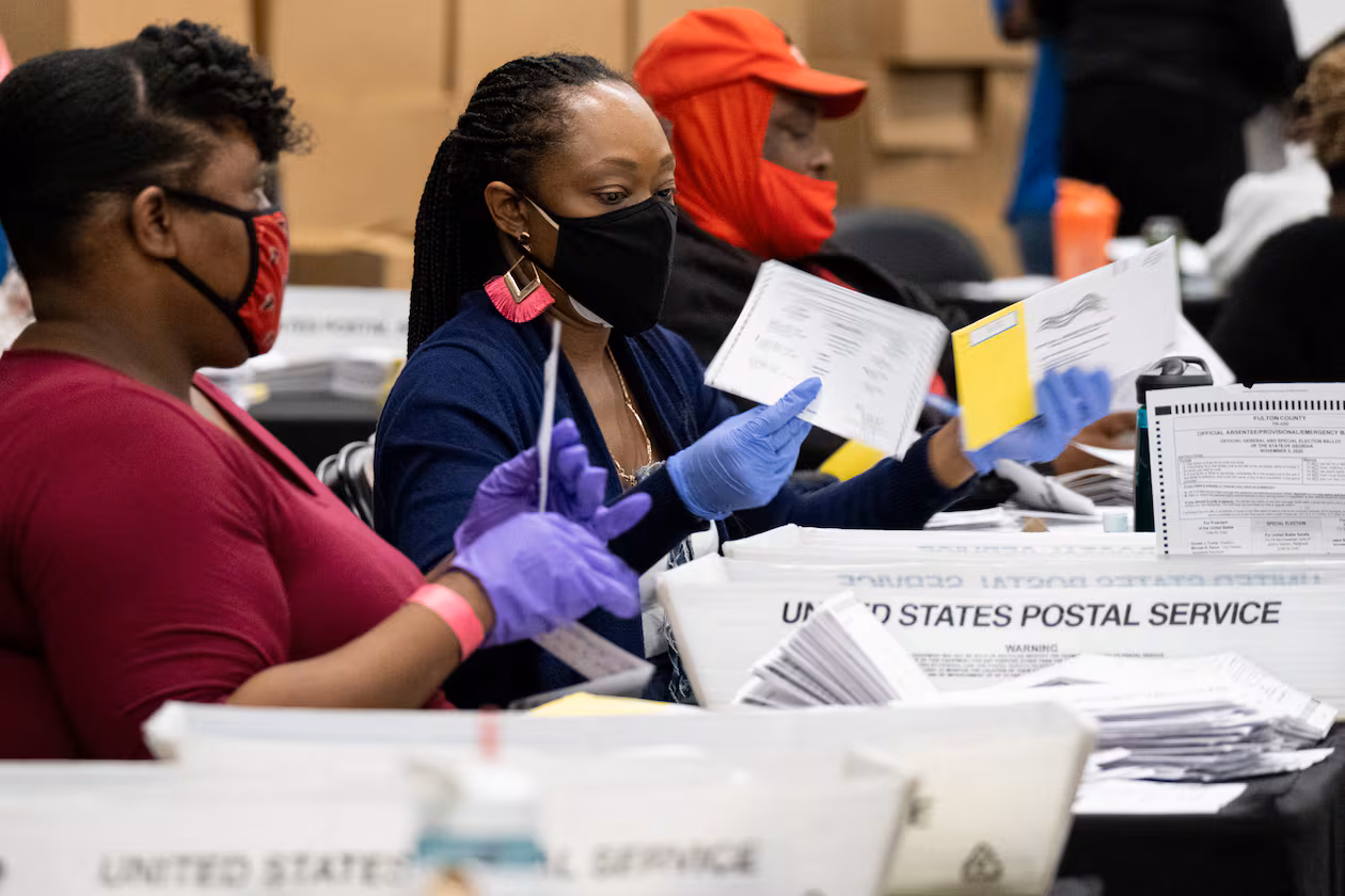 Workers sort mail-in and drop-off ballots at the Fulton County sorting center at State Farm Arena on Tuesday evening, Nov. 3, 2020, just before polls closed. (Ben Gray for the AJC)