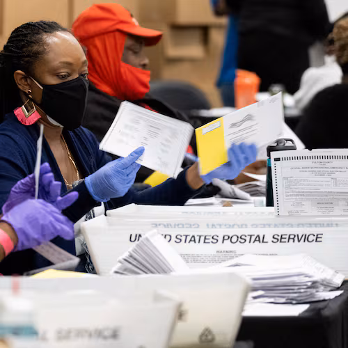 Workers sort mail-in and drop-off ballots at the Fulton County sorting center at State Farm Arena on Tuesday evening, Nov. 3, 2020, just before polls closed. (Ben Gray for the AJC)