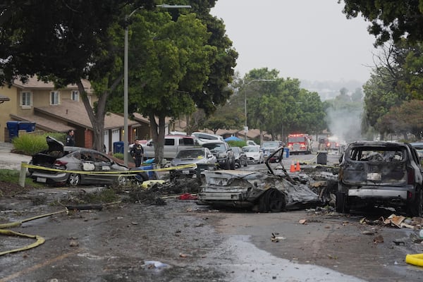 Authorities work the scene where a small plane crashed into a San Diego neighborhood, setting several homes on fire and forcing evacuations along several blocks early Thursday, May 22, 2025. (AP Photo/Gregory Bull)