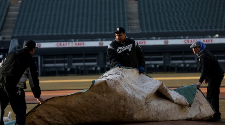 Nevest Coleman, center, helps Harry Smith Jr., left, and Jerry Powe with the tarp on Monday, March 26, 2018 at Guaranteed Rate Field in Chicago, Ill. (Nancy Stone/Chicago Tribune/TNS)