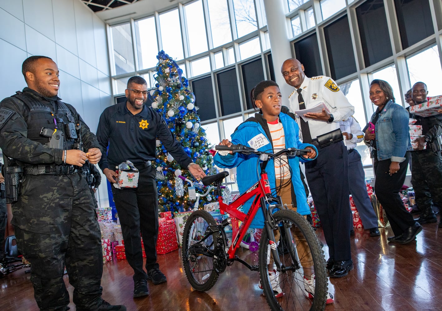 DeKalb County Sheriff’s Office holds the 16th annual Adopt-A-Family celebration on Tuesday, Dec 16, 2023 where Larry Sims is given a new bike. Law enforcement officers donate their own money and buy gifts for about a dozen local children.  (Jenni Girtman for The Atlanta Journal-Constitution)