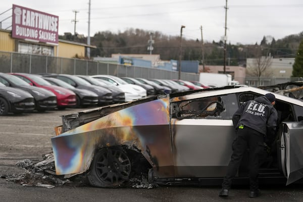 FILE - A member of the Seattle Fire Department inspects a burned Tesla Cybertruck at a Tesla lot in Seattle on March 10, 2025. (AP Photo/Lindsey Wasson, File)