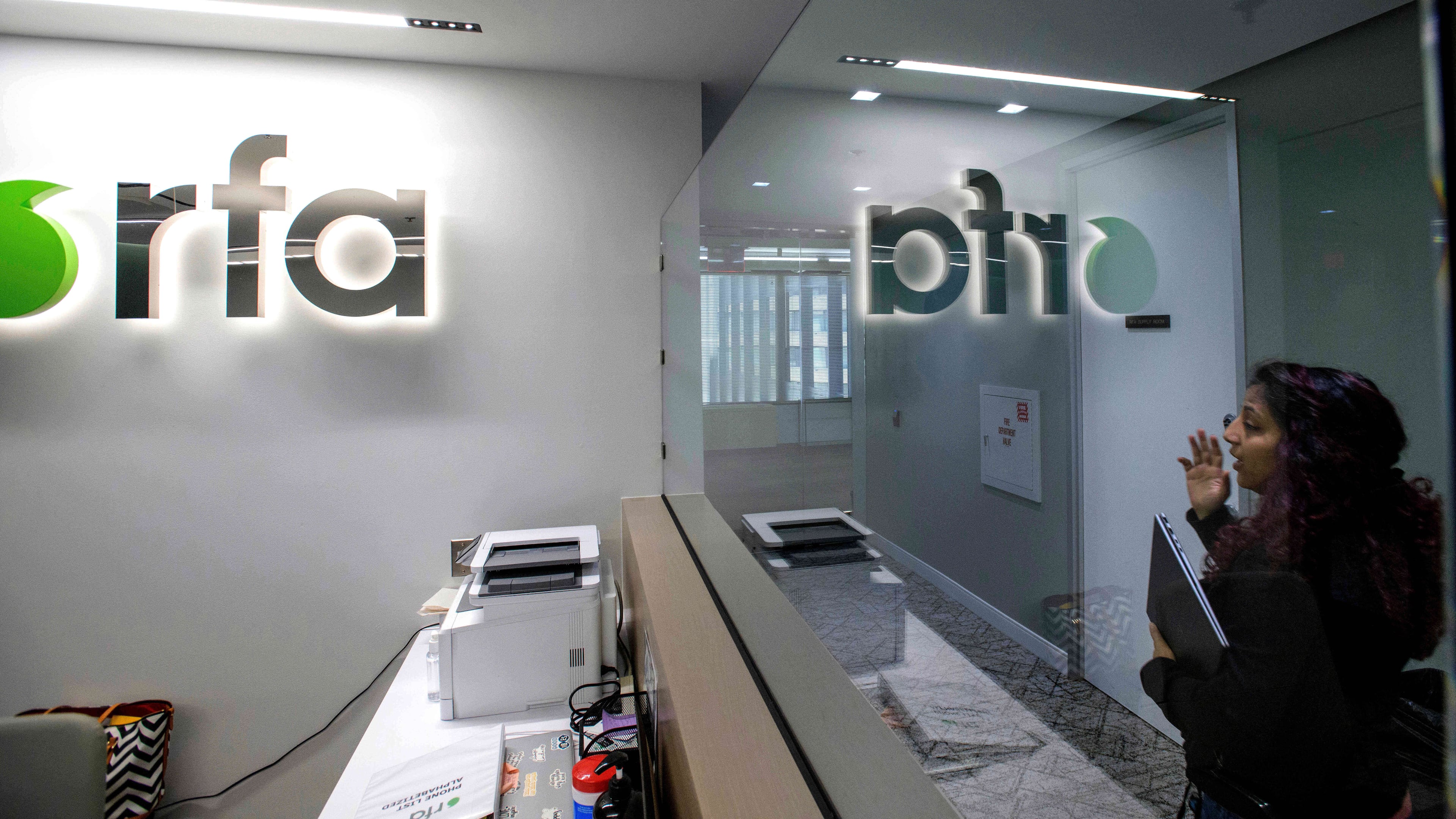 FILE - A woman walks past the empty receptionist desk at Radio Free Asia, April 1, 2025, in Washington. (AP Photo/Rod Lamkey, Jr., File)
