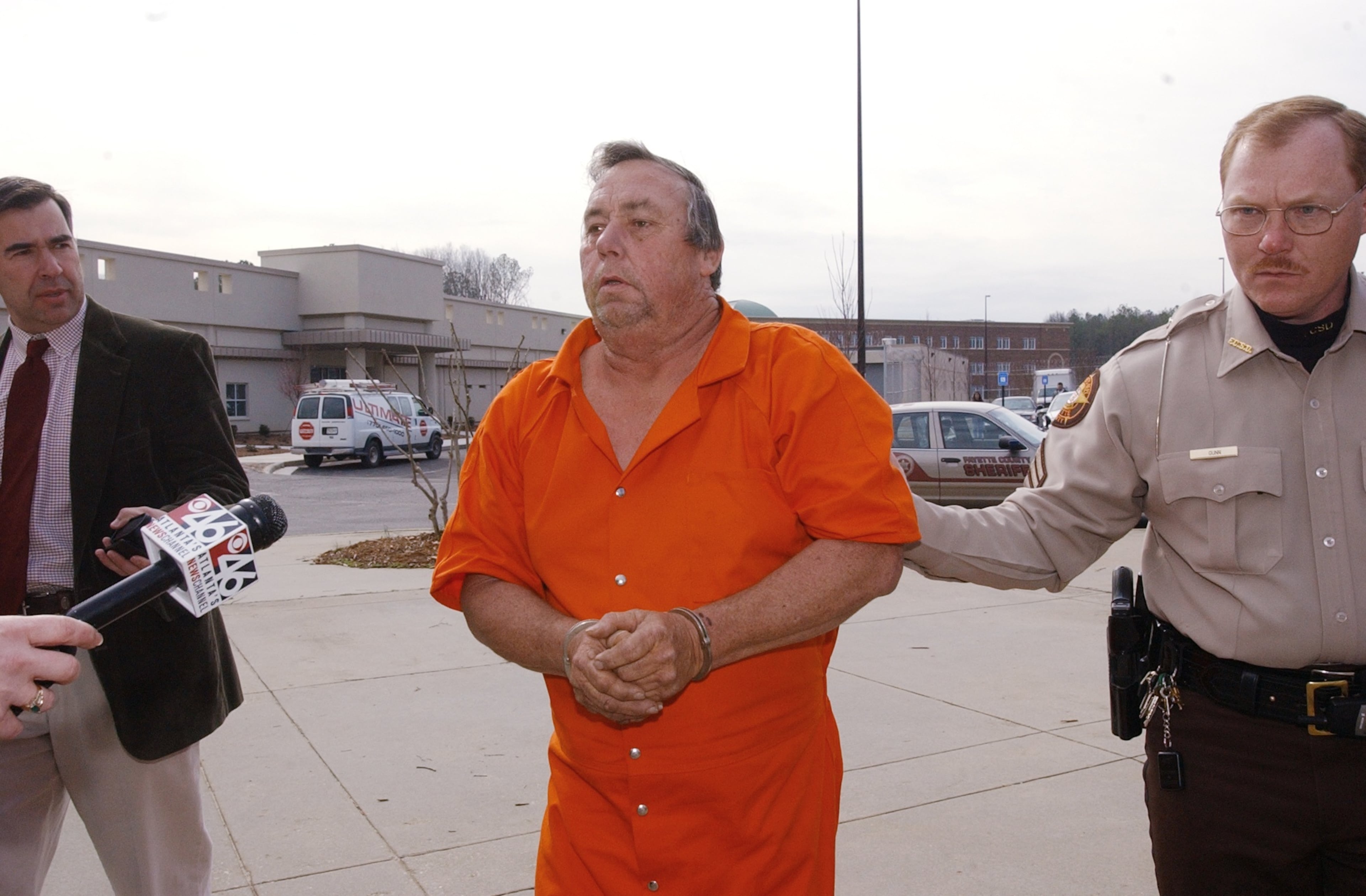 Carl M. Patton, Jr., 53, in orange jumpsuit, was convicted of four 1977 murders. He is escorted by Fayette County Sheriff's Corporal Jimmy Gunn, right. He was also the father of Melissa Wolfenbarger. (Kimberly Smith/AJC staff 2003)