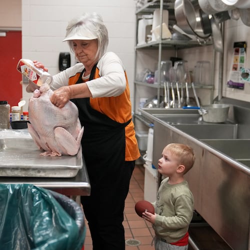 Kooper Keeland, 2, watches as his great-grandmother, high school cafeteria worker Shirley Mease, uses the kitchen at Reeds Spring High School to prepare 700 free Thanksgiving meals for community members Wednesday, Nov. 26, 2025, in Reeds Spring, Mo. (AP Photo/Jeff Roberson)