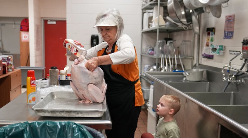 Kooper Keeland, 2, watches as his great-grandmother, high school cafeteria worker Shirley Mease, uses the kitchen at Reeds Spring High School to prepare 700 free Thanksgiving meals for community members Wednesday, Nov. 26, 2025, in Reeds Spring, Mo. (AP Photo/Jeff Roberson)