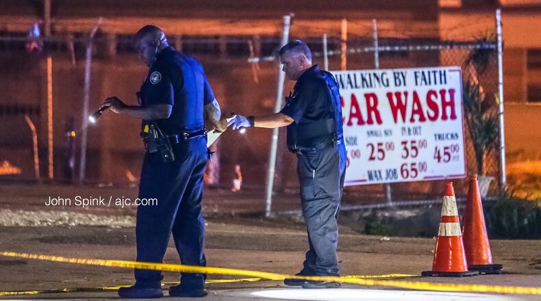 Officers search for evidence after two groups started shooting in the middle of Donald Lee Hollowell Parkway on Tuesday morning. A 19-year-old man was shot in the back.
