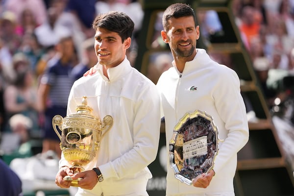 FILE - Carlos Alcaraz of Spain holds his trophy as he stands with Novak Djokovic of Serbia after winning the men's singles final at the Wimbledon tennis championships in London, Sunday, July 14, 2024. (AP Photo/Alberto Pezzali,File)