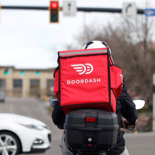 FILE - A food delivery rider waits at a traffic light, March 30, 2020, in Lone Tree, Colo. (AP Photo/David Zalubowski, File)