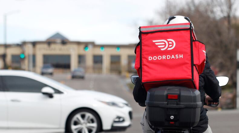 FILE - A food delivery rider waits at a traffic light, March 30, 2020, in Lone Tree, Colo. (AP Photo/David Zalubowski, File)