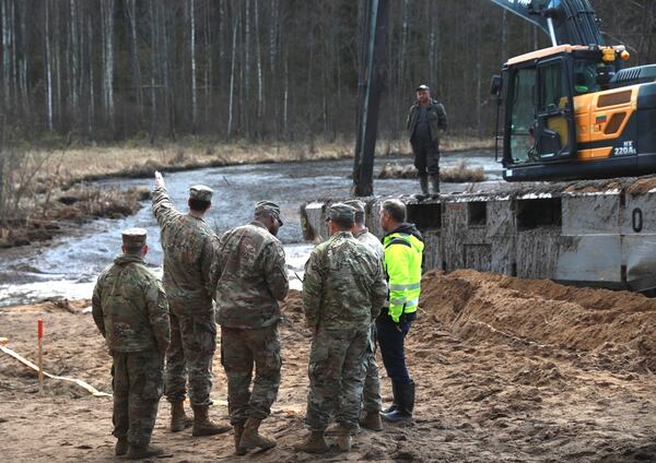 In this image provided by the U.S. Army, U.S. Army soldiers from the 1st Armored Brigade Combat Team, 3rd Infantry Division, along with Lithuanian Army and emergency services personnel, discuss their plan to recover four U.S. soldiers in a U.S. Army M88 Hercules submerged under several meters of water in a swamp near a training area near Pabadre, Lithuania, Thursday, March 27, 2025. (Trevor Wilson/U.S. Army via AP)