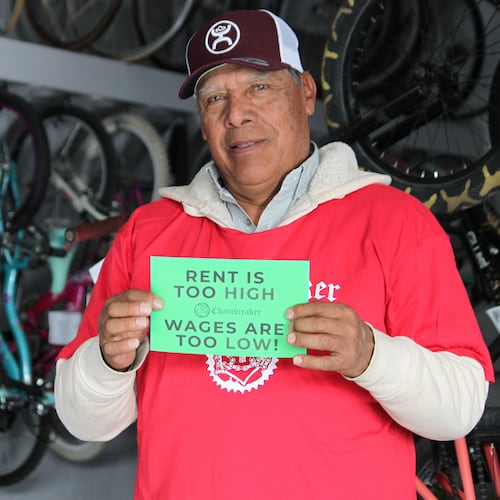 Ismael Cortes Estrada poses for a photo holding one of the signs advocates used in the campaign for updating the city's minimum wage law, in Santa Fe, New Mexico, on Wednesday, Nov. 26, 2025. (AP Photo/Susan Montoya Bryan)