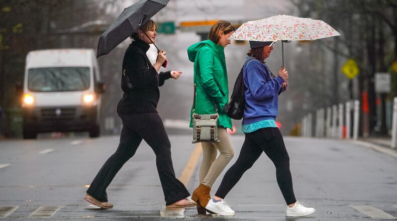 Three women walk across Tenth Street towards Piedmont Park on a rainy Tuesday. December 26th, 2023 (Ben Hendren for the Atlanta Journal-Constitution)