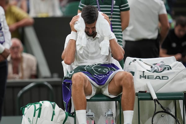 Novak Djokovic of Serbia places a cold towel around his head during a change of ends break against Alexandre Muller of France during their first round men's singles match at the Wimbledon Tennis Championships in London, Tuesday, July 1, 2025. (AP Photo/Kin Cheung)