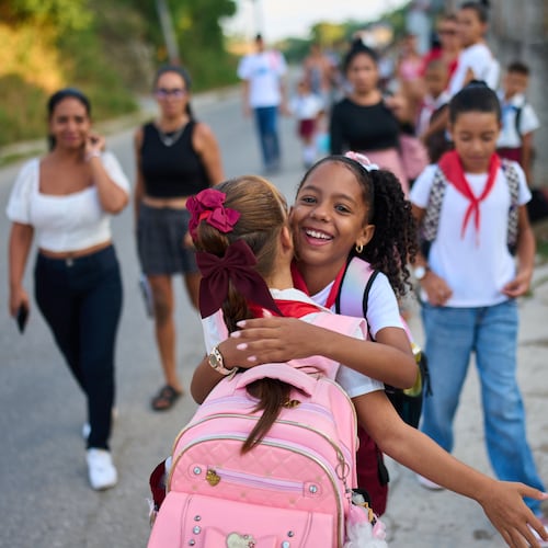 Girls hug as they arrive to school for their first day back to classes in Minas, Cuba's Havana province, Tuesday, Sept. 1, 2026. (AP Photo/Ramon Espinosa)