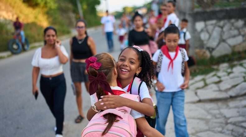 Girls hug as they arrive to school for their first day back to classes in Minas, Cuba's Havana province, Tuesday, Sept. 1, 2026. (AP Photo/Ramon Espinosa)