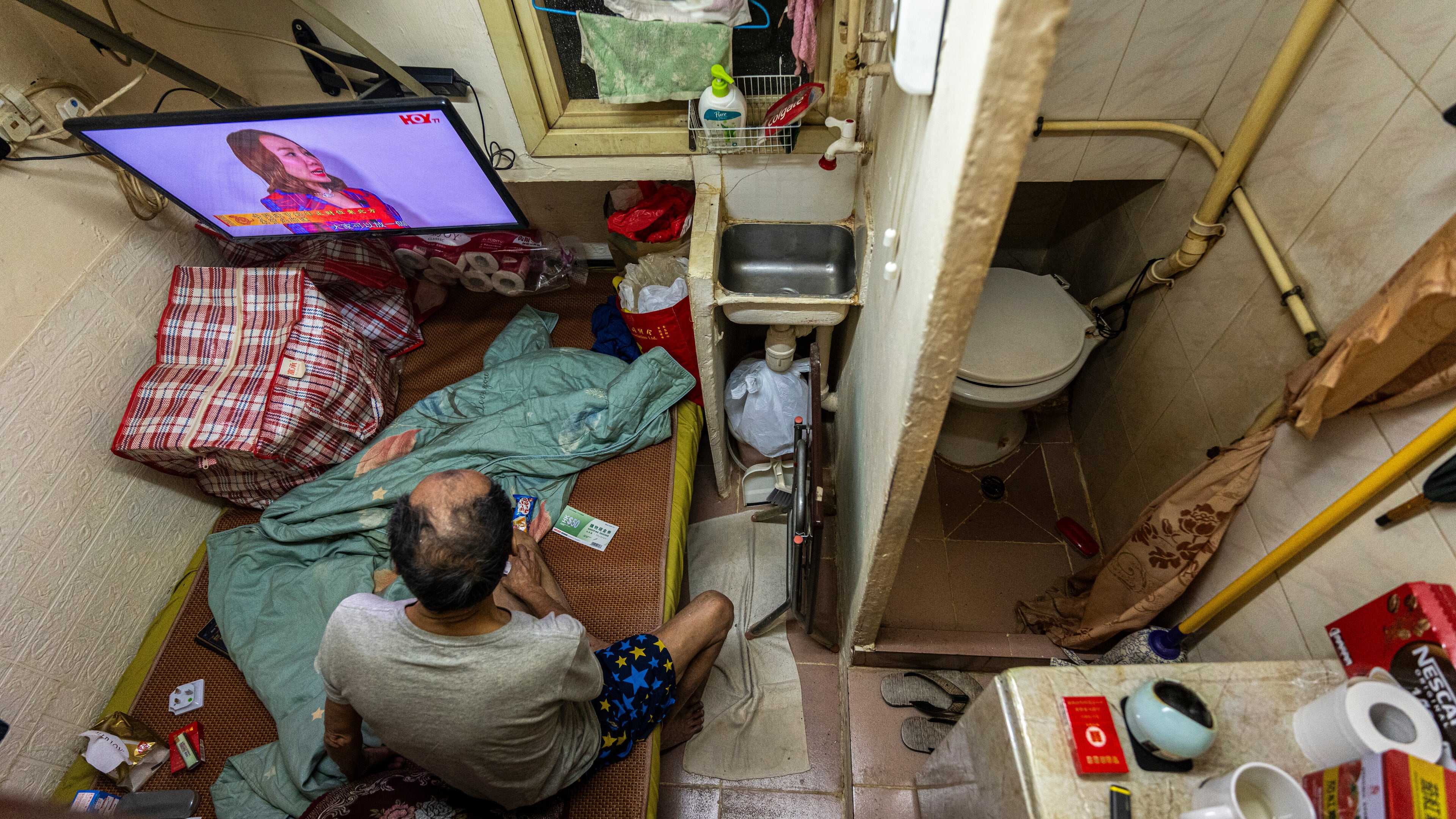 FILE - A resident who gave his name as Cheung watches television at his subdivided flat in Sham Shui Po district of Hong Kong, Feb. 6, 2025. (AP Photo/Chan Long Hei, File)