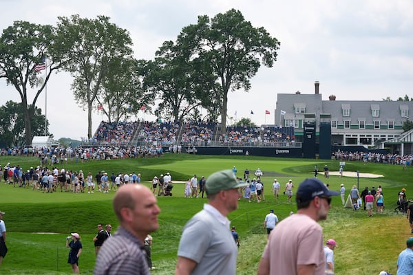 Fans cross the 18th fairway, in front of the green and clubhouse, between groups of golfers during a practice round for the 2025 US Open golf championship at Oakmont Country Club in Oakmont, Pa., Monday, June 9, 2025. (AP Photo/Gene J. Puskar)