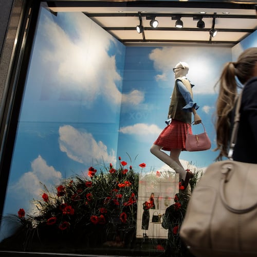 FILE - A woman walks past the Gucci store window at the Via Montenapoleone fashion district during Milan's fashion week in Milan, Italy, Sept. 25, 2020. (AP Photo/Luca Bruno, File)