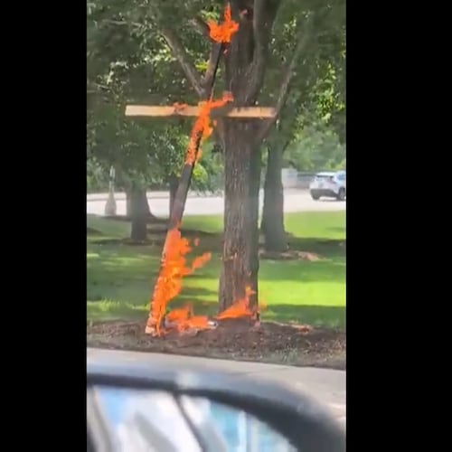 This grab from a video taken by motorist Keinika Carlton shows a wooden cross engulfed in bright orange flames as it leans against a tree in Grant Park, Chicago, Illinois, on Tuesday, July 9, 2026.(Keinika Carlton via AP)