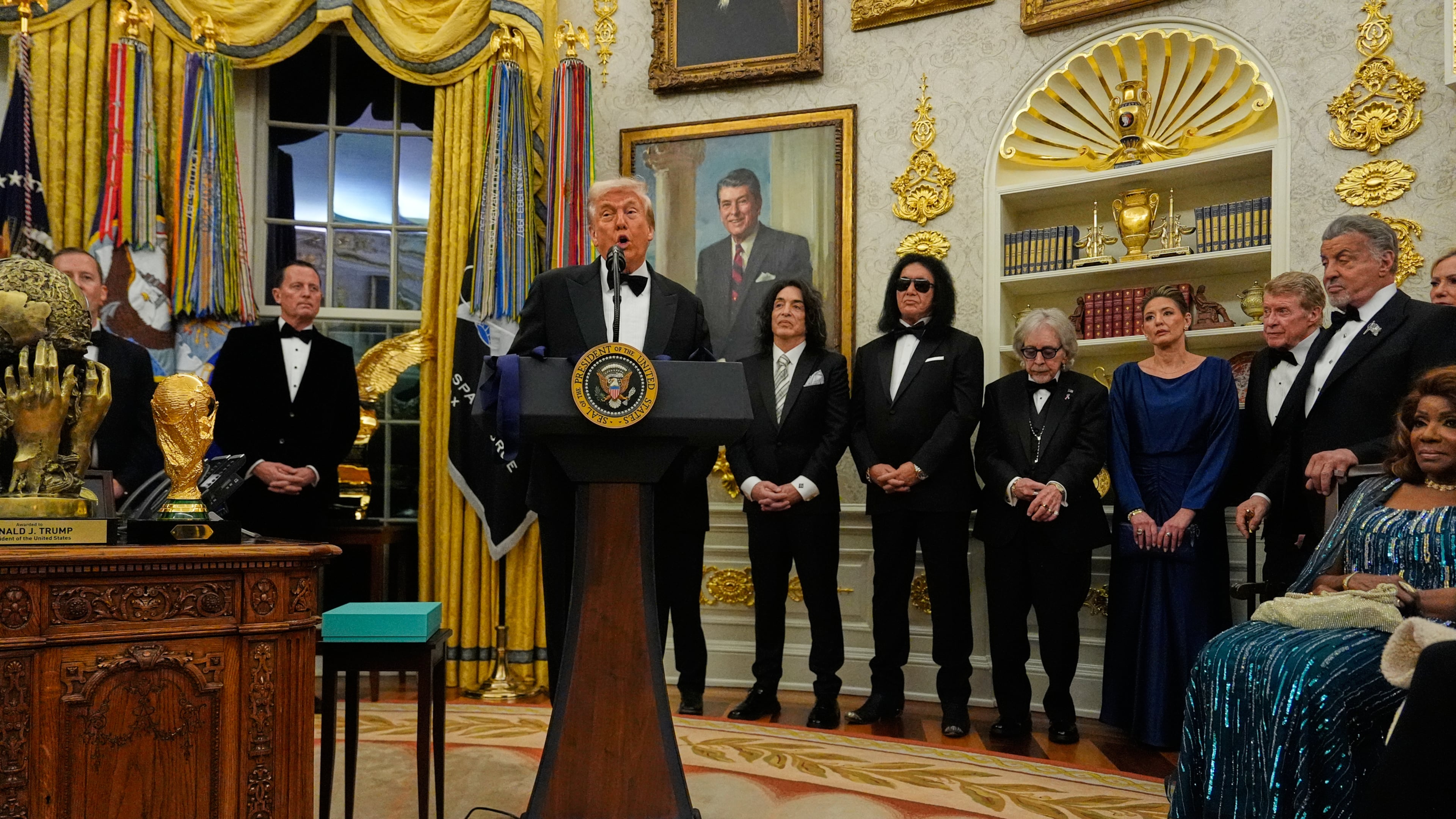 President Donald Trump, center, speaks as he presents Sylvester Stallone, George Strait, KISS, Gloria Gaynor and Michael Crawford with their Kennedy Center Honors medals in the Oval Office of the White House, Saturday, Dec. 6, 2025, in Washington. (AP Photo/Julia Demaree Nikhinson)