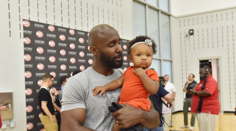 Hawks head coach Lloyd Pierce holds his daughter Maya Joy Pierce. HYOSUB SHIN / HSHIN@AJC.COM