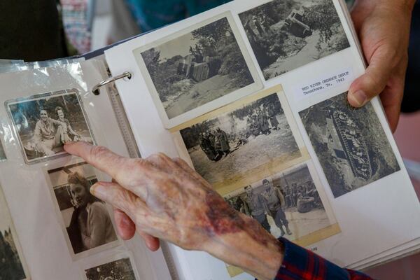 Avery Low points to photographs in a scrapbook documenting his military service. He landed at Utah Beach with the U.S. Army’s 537th Ordnance Heavy Maintenance Field Army shortly after D-Day. (Walker Smith for the AJC)