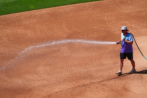 Coors Field head groundskeeper Mark Razum wets down the skin of the infield for a baseball game between the Arizona Diamondbacks and the Colorado Rockies as a heat dome packing triple-digit daytime high temperatures sweeps over the intermountain west Friday, June 20, 2025, in Denver. (AP Photo/David Zalubowski)